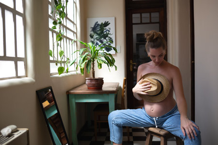young beautiful pregnant woman looks in a large mirror while sitting in her authentic vintage...