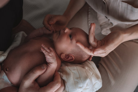 a newborn baby lies in the arms of his young father and mother. the concept of happy and conscious...
