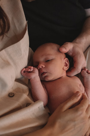 a newborn baby lies in the arms of his young father and mother. the concept of happy and conscious parenthood.の写真素材
