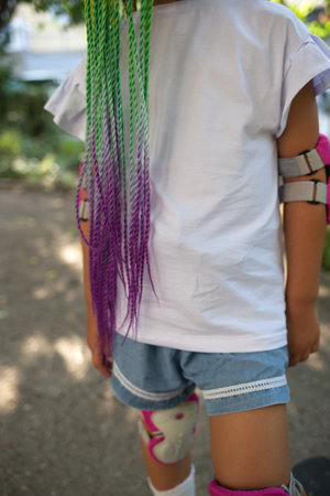 little cute girl with colorful afro pigtails standing on a skateboardの写真素材