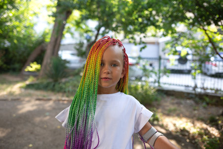 portrait of a little beautiful girl with multi-colored african braidsの写真素材