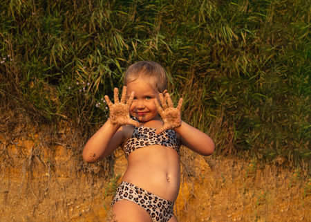 little cute girl in an animal print swimsuit posing on the beach near the seaの写真素材