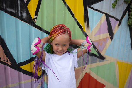 portrait of a little beautiful girl with multi-colored pigtails on the background of a colorful wall.の写真素材