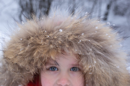 close-up shot. portrait of a little girl with snowflakes on her hood.の写真素材