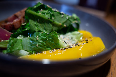 fresh bright juicy tuna and mango salad with spinach on a beautiful gray plate.の写真素材