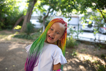 portrait of a little beautiful girl with multi-colored african braidsの写真素材