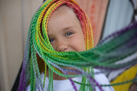 portrait of a little beautiful girl with multi-colored pigtails on the background of a colorful...