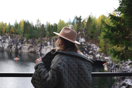 portrait of a beautiful young woman with freckles in a hat on the background of a lake surrounded by treesの写真素材