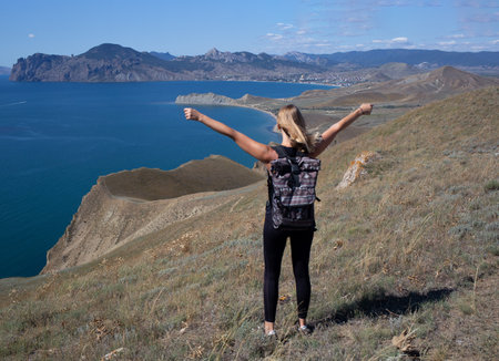 young woman hiker stands on the mountain against the background of the seaの写真素材
