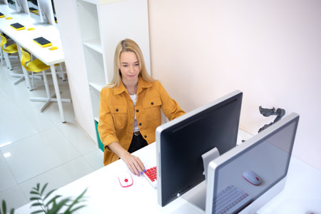 young woman sits at a computer in the office. remote work conceptの写真素材
