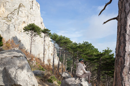 young woman hiker sits on a stone on a background of mountainsの写真素材