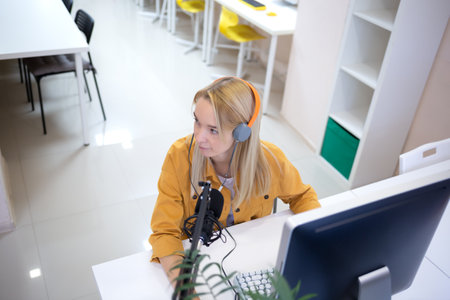 young woman is streaming while sitting in coworking at the computerの写真素材