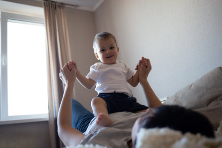 little boy plays with young beautiful mom in the bedroomの写真素材