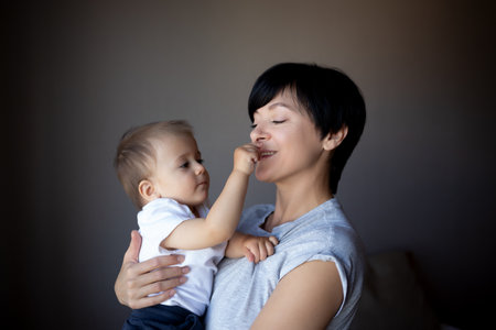 little boy plays with young beautiful mom in the bedroomの写真素材
