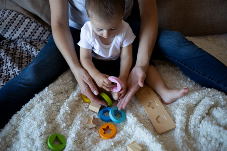 little boy plays with young beautiful mom in the bedroom.