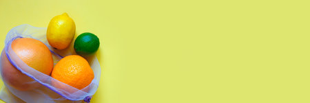 ripe juicy citrus fruitsin in reusable eco friendly bag on a yellow background.の写真素材