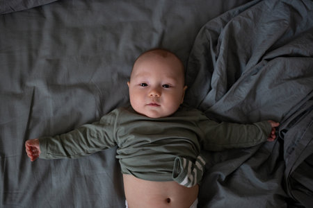 mixed race newborn baby lies wrapped in a grey muslin swaddle.の写真素材