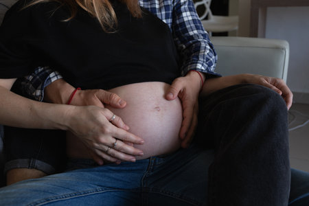 A loving couple embraces, their hands gently resting on her pregnant belly, sharing a tender moment...