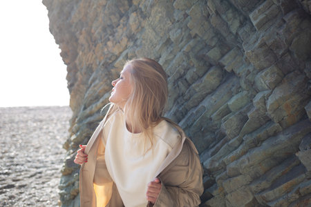 portrait of a young beautiful woman on the seashore against the background of rocksの写真素材