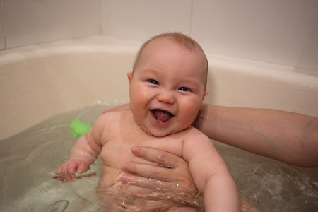 A joyful baby enjoying a warm bath, smiling with pure happiness and innocence.の写真素材