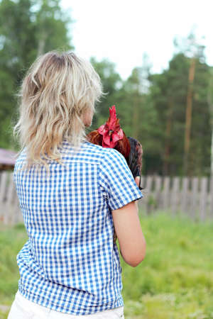Beautiful woman in the farm holding a chicken, healthy lifestyleの写真素材