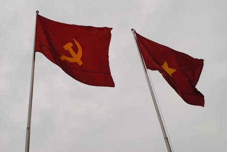 Two red flags with yellow star and hammer and sickle on the background grey skyの写真素材