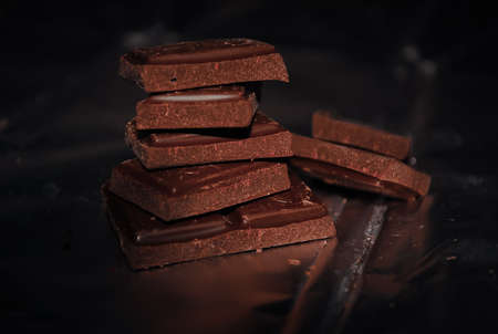Stack of bitter chocolate slices on a foilの写真素材