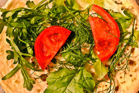 Russian pancake with fresh arugula, parsley, dill and slices of tomato. Close upの写真素材