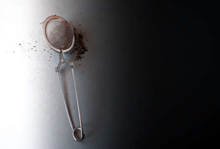 Tea strainer with black tea on a black and white background
