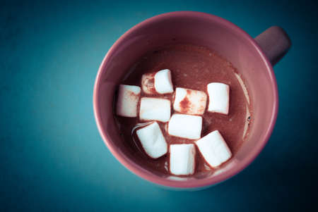 Pink cup of cocoa with marshmallows on dark turquoise backgroundの写真素材