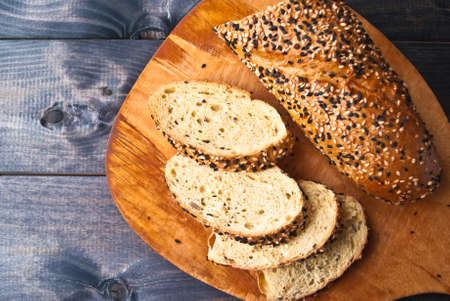 Slices of fresh homemade baguette with sesame served on beige cutting boardの写真素材