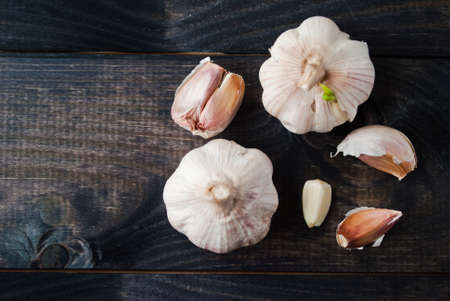 Whole heads of fresh garlic and a few cloves on dark wooden table. Top viewの写真素材