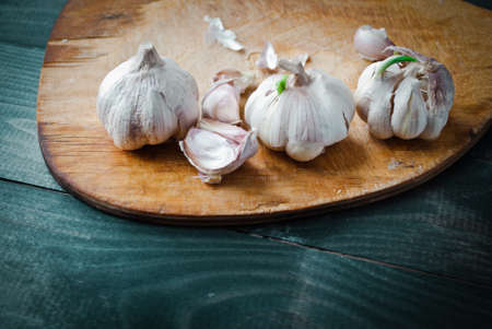 Fresh raw garlic on beige cutting board and turquoise wooden table. Top viewの写真素材