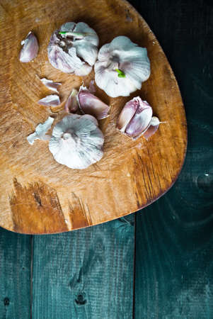 Fresh raw garlic on beige cutting board and dark turquoise wooden table. Top viewの写真素材