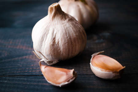 Whole heads of fresh garlic and a few cloves on dark blue wooden tableの写真素材