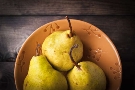 Yellow pears in a beige bowl on rustic background. Close upの写真素材