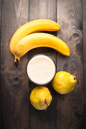 Smoothie and fresh bananas and pears on wooden background. Top viewの写真素材