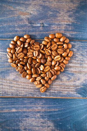 Heart shape made from coffee beans on blue wooden backgroundの写真素材