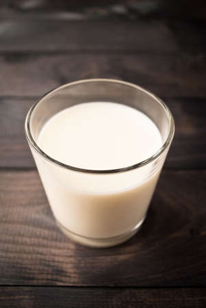 Full glass of milk on brown wooden backgroundの写真素材
