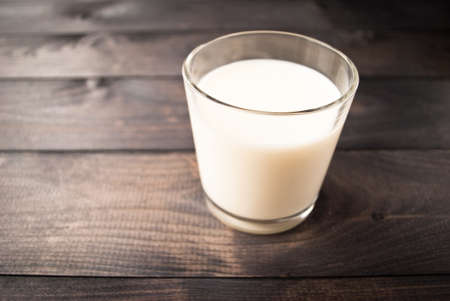 Full glass of milk on brown rustic wooden backgroundの写真素材
