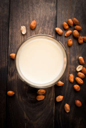 Full glass of milk and peanuts on rustic wooden background. Top viewの写真素材