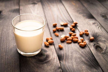 Full glass of milk and peanuts on rustic wooden backgroundの写真素材