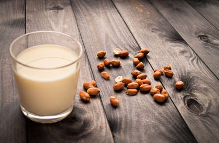 Glass of milk and peanuts on rustic wooden backgroundの写真素材