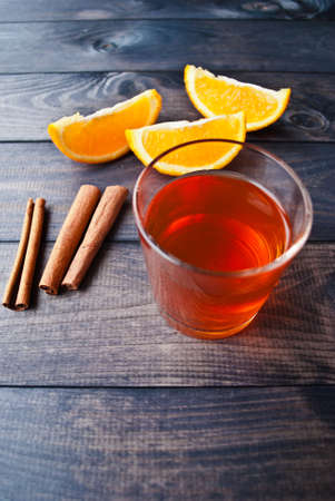 Glass cup of black tea, cinnamon sticks and orangesの写真素材