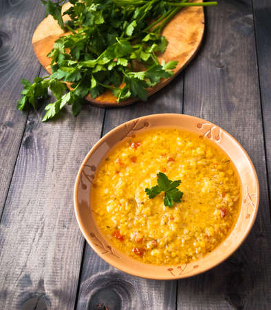 Red lentil soup in ceramic bowl and parsley on wooden backgroundの写真素材