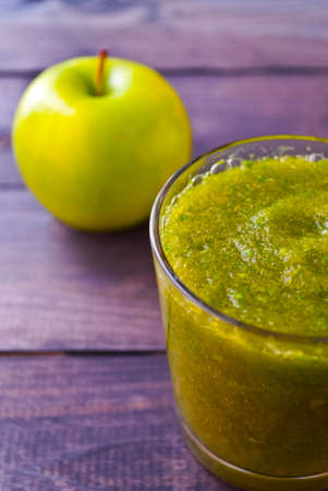 Green smoothie in glass and apple on wooden backgroundの写真素材