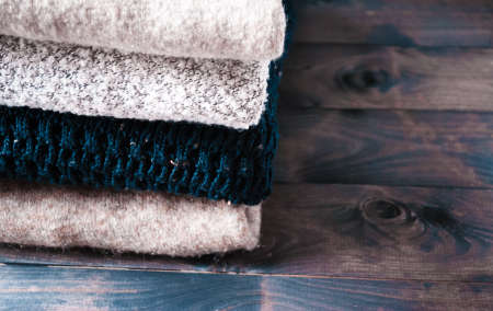 Stack of knitted clothes on rustic wooden backgroundの写真素材