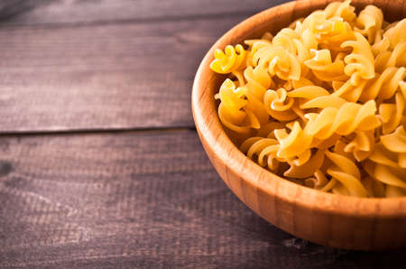 Raw pasta in bowl on wooden background. Close upの写真素材