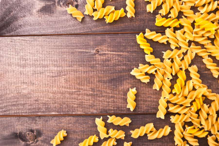 Raw pasta on rustic wooden surface as a frameの写真素材