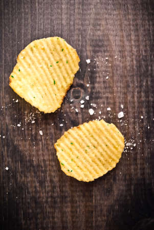 Corrugated potato chips and salt on wooden background. Top viewの写真素材